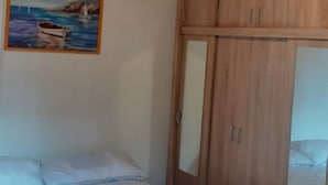 A bedroom with a bed, a wooden wardrobe, and a painting of a boat on the wall. - Apartments Rudi - One Bedroom Apartment With Terrace (Novi Vinodolski)