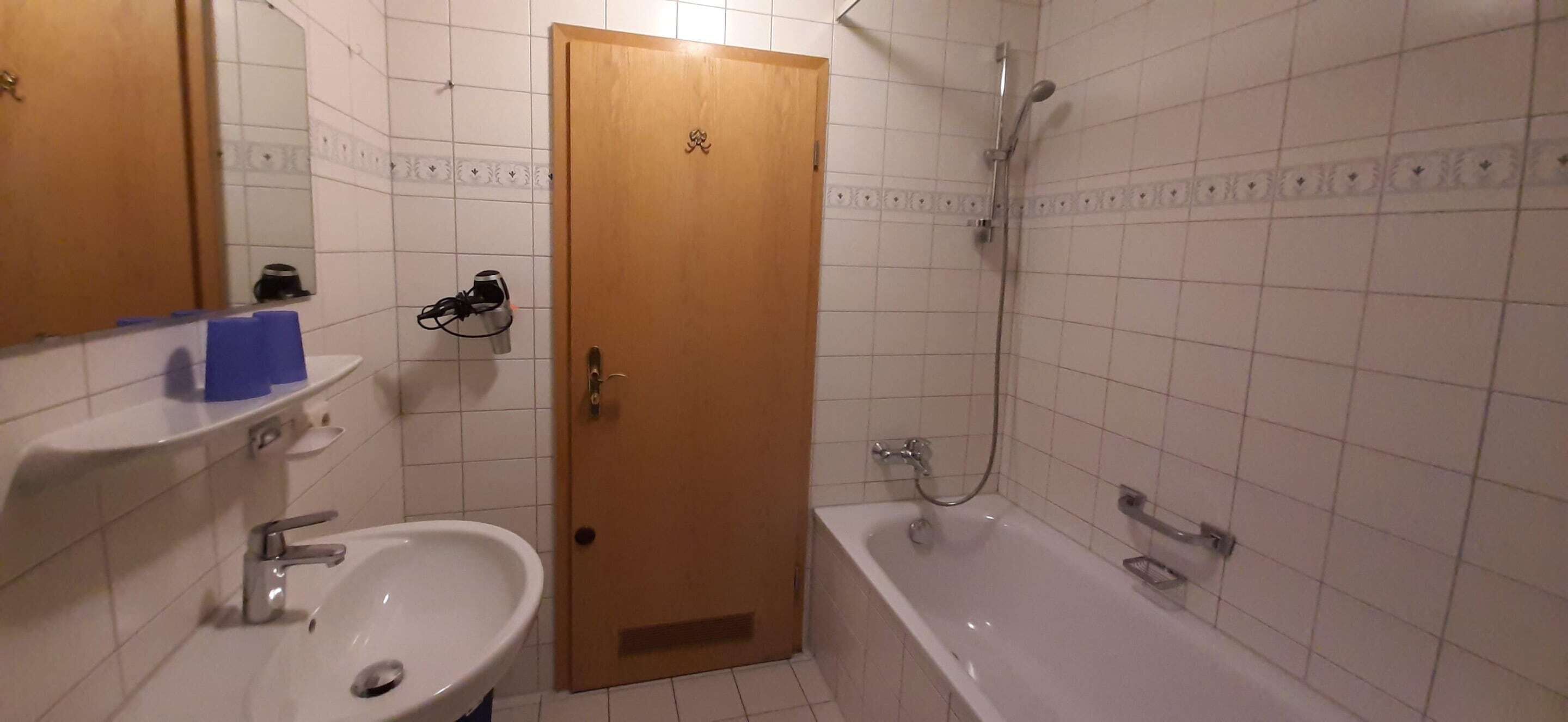 A bathroom with a sink, mirror, and shower.
