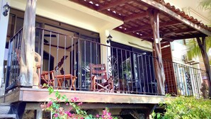 A wooden balcony with metal railings, a stone wall, and a wooden staircase leading to the upper floor. - Amazing ocean view condo, steps to the beach, 3 pools, gated community (Playa Ocotal)