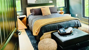 Une chambre à coucher moderne avec un grand lit, un ventilateur de plafond et deux fenêtres.