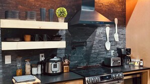 Une cuisine moderne dotée d’un plan de travail noir, de meubles en bois, d’une cuisinière en acier inoxydable et d’une hotte noire.