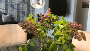 Une table à manger sur laquelle se trouve un vase en verre transparent contenant une plante aux feuilles vertes et aux fleurs roses.