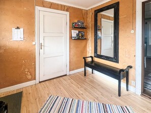 A hallway with a wooden floor, a white door, a black bench, and a mirror on the wall. - 7 Person Holiday Home in Forsheda (Forsheda)