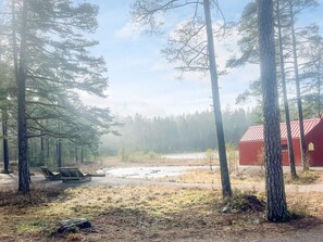 A forested area with a red building, a bench, and a small clearing. - 7 Person Holiday Home in Forsheda (Forsheda)
