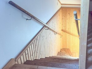 Un escalier en bois avec une rampe métallique et un mur en bois.