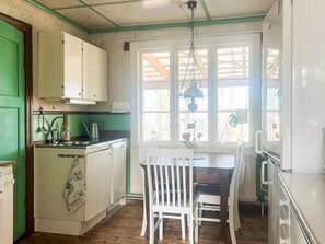 A kitchen with a dining area, wooden cabinets, a sink, and a window with a view. - 7 Person Holiday Home in Forsheda (Forsheda)