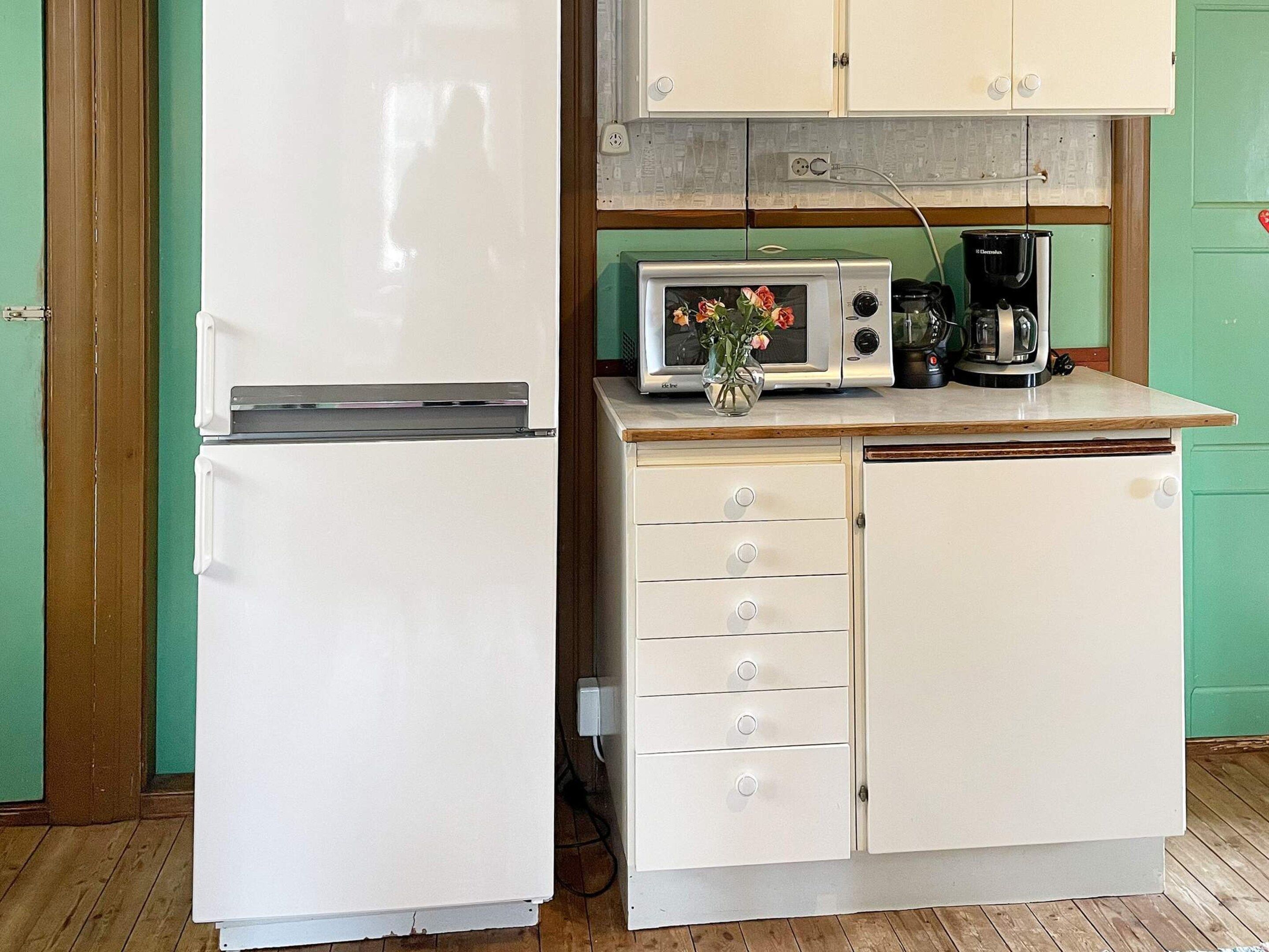 A compact kitchen with a white refrigerator, a microwave, and a coffee maker on the countertop.