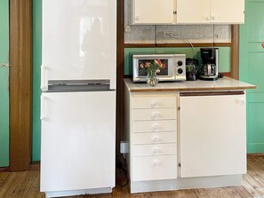 A compact kitchen with a white refrigerator, a microwave, and a coffee maker on the countertop. - 7 Person Holiday Home in Forsheda (Forsheda)