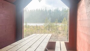 A wooden cabin with a large window and a picnic table. - 7 Person Holiday Home in Forsheda (Forsheda)