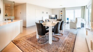 Ein modernes Hotelzimmer mit Essbereich, einem großen Spiegel, einem Flachbildfernseher und einer Sitzecke mit Blick auf die Stadt.