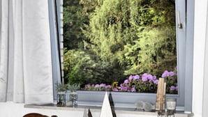 A wooden dining table with a white sailboat model, a glass, and a candle. - Holiday Apartment Green House (Aumuehle)