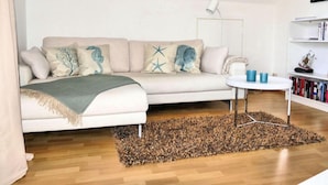 A modern living room with a beige sofa, a small round table, and a bookshelf. - Holiday Apartment Green House (Aumuehle)