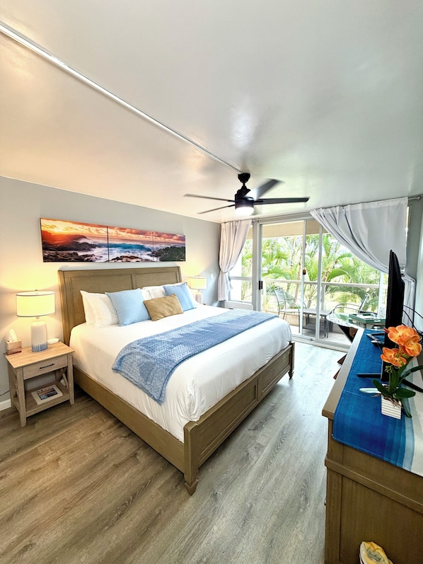 A bedroom with a bed, bedside table, lamp, and a view of the outdoors.