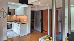 A modern kitchen with white cabinets, a built-in oven, and a wooden countertop.