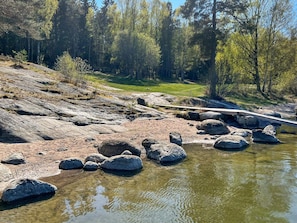 A rocky riverbank with a wooden bridge and a forest in the background. - 6 Person Holiday Home in Varmdo-by Traum (Värmdö)