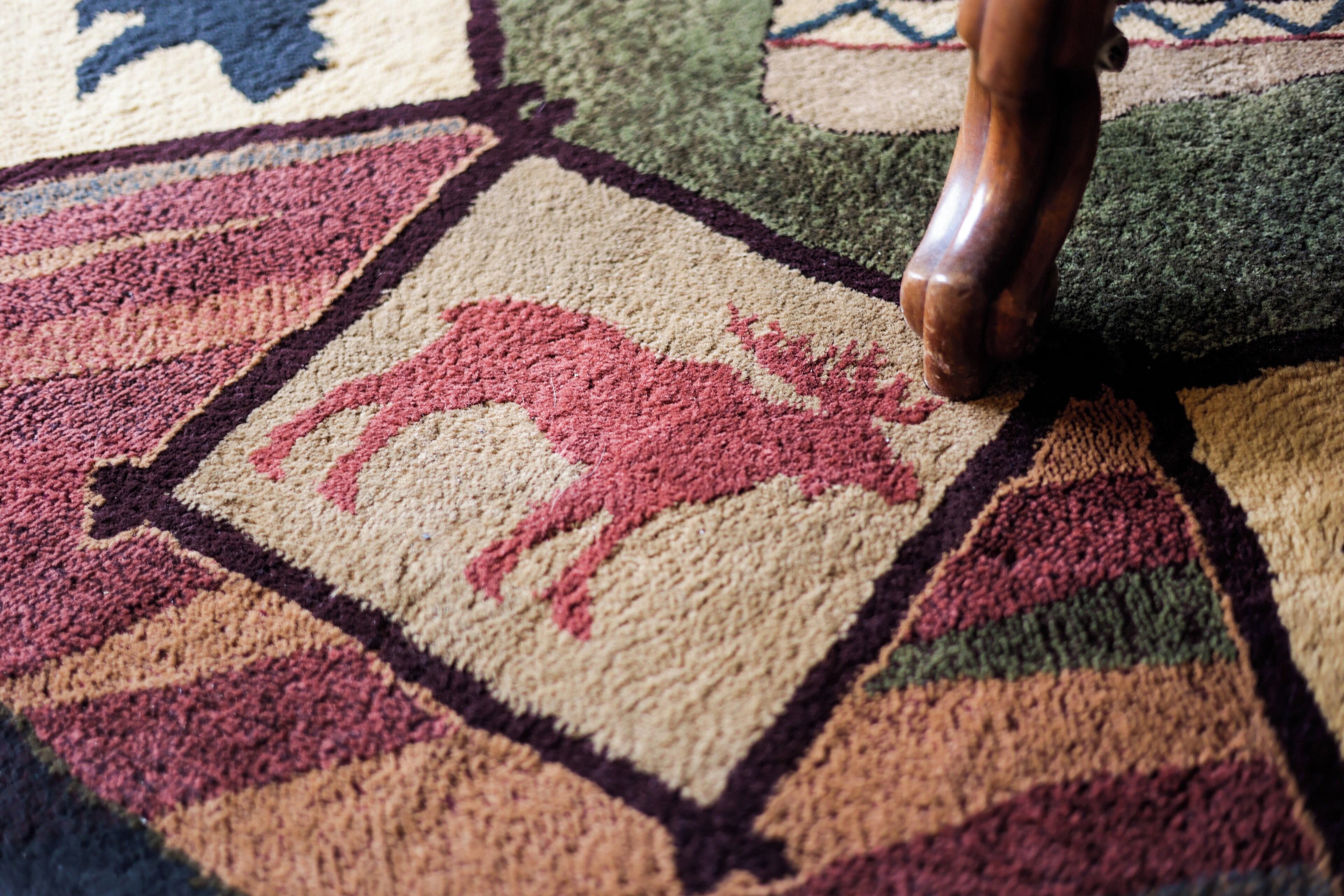 A close-up of a carpet with a geometric pattern and a central animal motif.