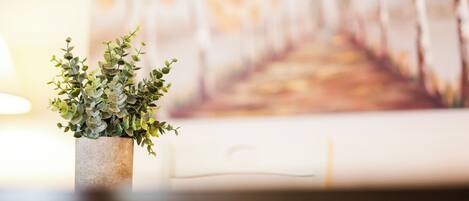 A potted plant on a table with a blurred painting in the background.