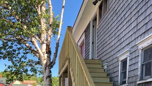 A wooden staircase with a handrail leading up to a house with a dark siding exterior.