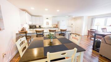 Una cocina moderna con armarios blancos, una isla central y un área de comedor con mantel a cuadros.
