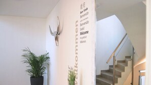 Et moderne interiør med trappe, velkommenskilt og potteplanter.