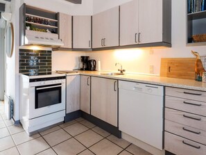 A modern kitchen with light wood cabinets, a white stove, and a dishwasher. - 6 Person Holiday Home in Hadsund (Hadsund)
