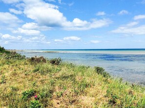 A coastal landscape with a clear sky, calm sea, and grassy foreground. - 6 Person Holiday Home in Hadsund (Hadsund)