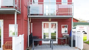 Punainen rakennus, jossa on parveke, ja sen edessä on pöytä ja tuoleja.