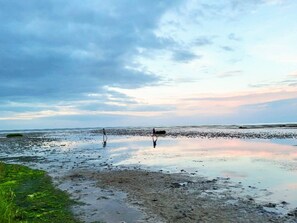 A beach with a calm sea, a cloudy sky, and a person walking. - 6 Person Holiday Home in Hadsund (Hadsund)