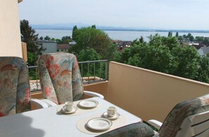 Ein Balkon mit Tisch für Zwei, mit Blick auf ein Gewässer und eine Stadtlandschaft.