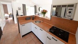 A modern kitchen with white cabinets, a stainless steel sink, and a built-in stove. - Spacious Holiday Home With Terrace (Zevenhuizen)