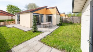 A modern house with a patio, a small garden, and a wooden fence. - Spacious Holiday Home With Terrace (Zevenhuizen)