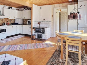A kitchen with white cabinets, a stove, and a dining area with a table and chairs. - 4 Star Holiday Home in Ljusdal (Ljusdal)
