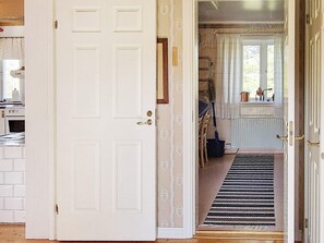 A white door leading to a room with a radiator, a window with curtains, and a striped rug on the floor. - 4 Star Holiday Home in Ljusdal (Ljusdal)