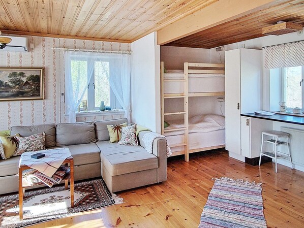 A cozy room with a sofa, a bunk bed, a desk, and a window.