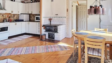 A kitchen with white cabinets, a stove, and a dining area with a table and chairs.