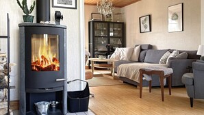 Un salon chaleureux avec un poêle à bois, un canapé, une table basse et une bibliothèque.