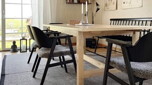 Un coin repas avec une table et des chaises en bois, une bibliothèque et des illustrations botaniques accrochées au mur.