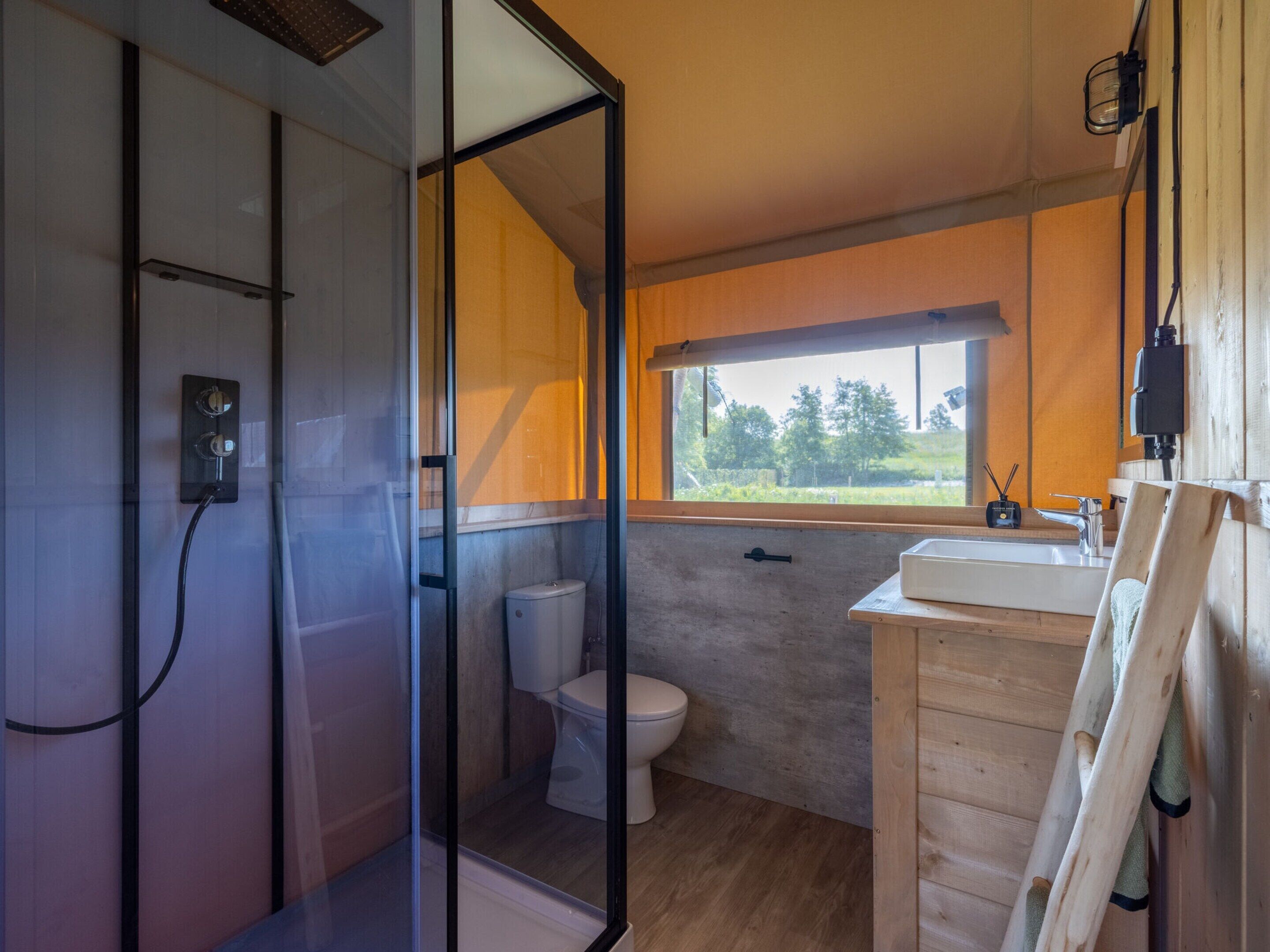 A modern bathroom with a glass shower enclosure, a toilet, and a wooden vanity with a sink.