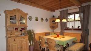 Un rincón comedor acogedor con muebles de madera, una mesa con mantel verde y una ventana con cortinas.