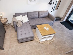 A modern living room with a grey sectional sofa, a wooden coffee table, and a small side table with a lamp. - 5 Star Holiday Home in Hovborg (Hovborg)