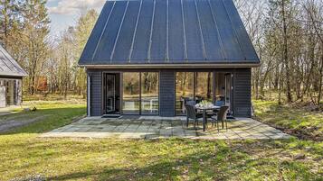 Uma casa moderna com varanda coberta, grandes portas de correr de vidro e telhado de metal.
