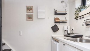 A modern kitchen with white cabinetry, a stainless steel sink, a coffee maker, and a small trash bin. - 5 Star Holiday Home in Hovborg (Hovborg)