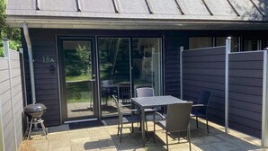 A patio with a table and chairs, a barbecue grill, and a sliding glass door. - 5 Star Holiday Home in Hovborg (Hovborg)