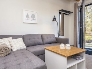 A modern living room with a grey sectional sofa, a wooden coffee table, and a framed artwork on the wall. - 5 Star Holiday Home in Hovborg (Hovborg)