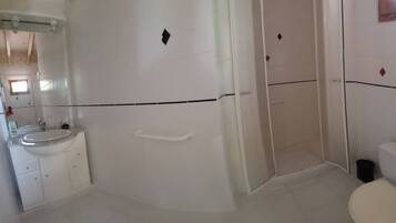 Une salle de bain comprenant un lavabo, des toilettes et un espace douche.