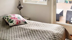 Un dormitorio con cama, ventana y vista a una terraza exterior.
