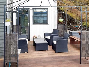 Eine überdachte Terrasse mit Korbmöbeln, einem Tisch und einer hängenden Leuchte.