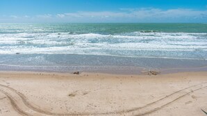 Una playa con cielos despejados y olas tranquilas.