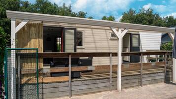 A single-story mobile home with a porch, a fenced yard, and a wooden deck.