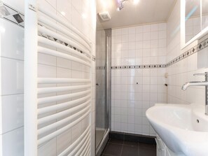 Un baño moderno con cabina de ducha de vidrio, un lavabo blanco y un perchero para toallas.